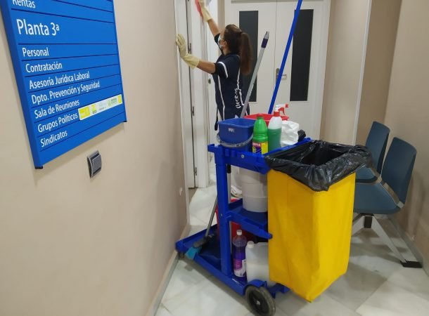 Persona limpiando pasillo con carrito de limpieza