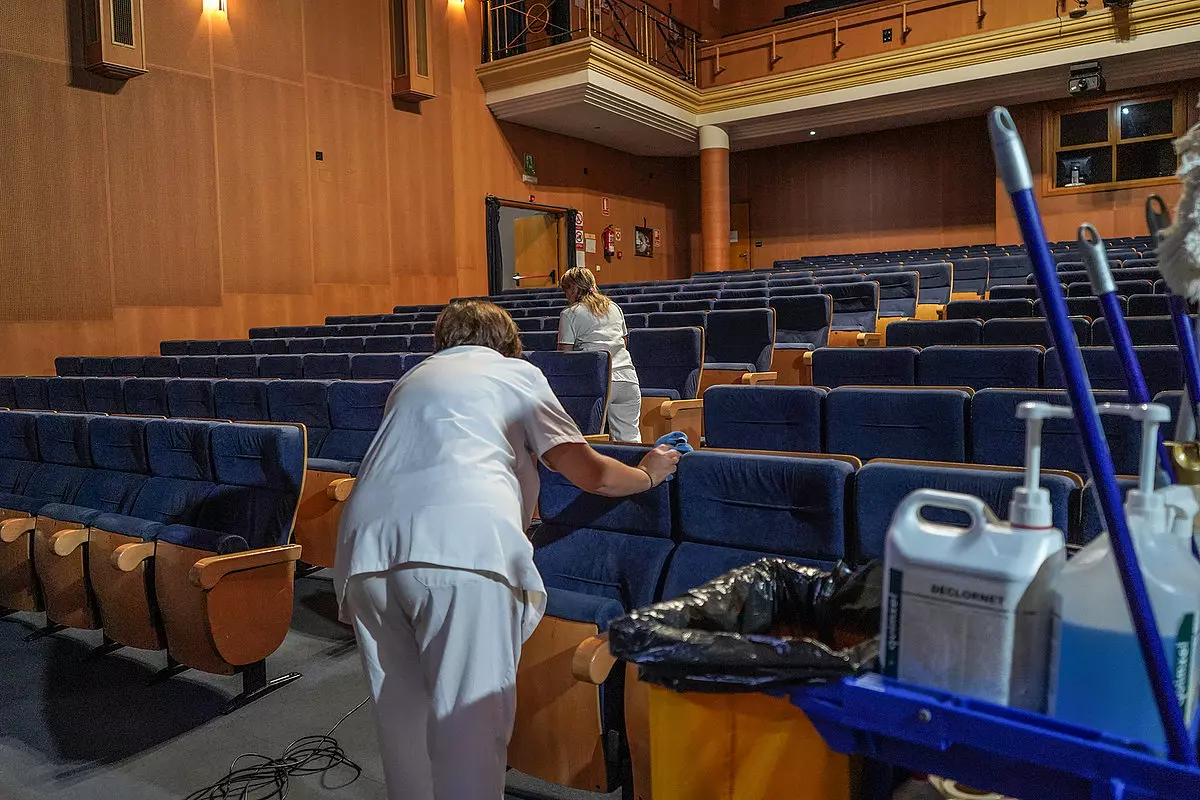 Limpiadoras desinfectando asientos de un teatro vacío.